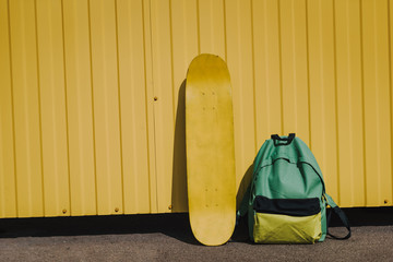 Close up yellow skateboard and sack near fence © Yakobchuk Olena