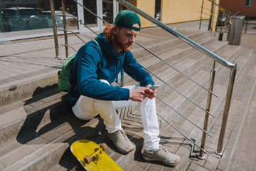 Skater man messaging on mobile phone on stairs