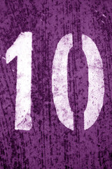 Number 10 in stencil on metal wall in purple tone.
