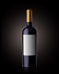 A bottle of red wine on a black background, with a clear label.