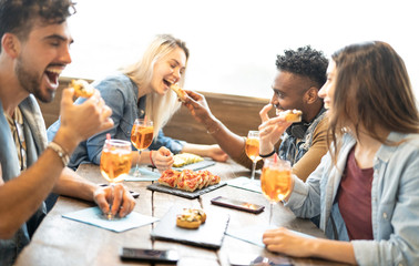 Friends eating and drinking spritz at fashion cocktail bar restaurant - Friendship concept with young people having fun together with drinks and food on happy hour at pub - Focus on pizza slices - obrazy, fototapety, plakaty