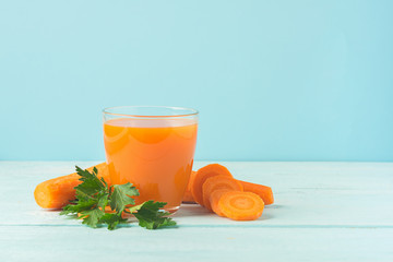 A glass of fresh carrot juice on a wooden blue background. Selective focus. Copy space.