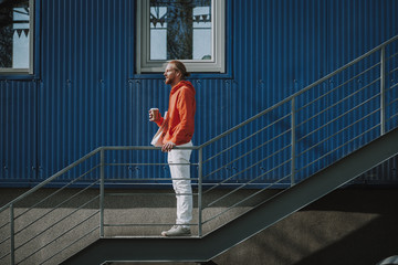 Young hipster man with coffee on outdoor stairs