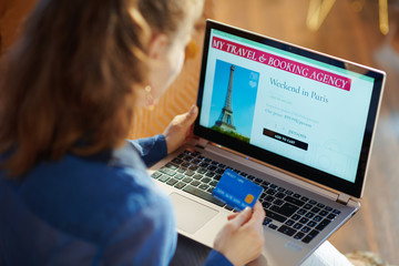 woman with online travel site on laptop holding blue credit card