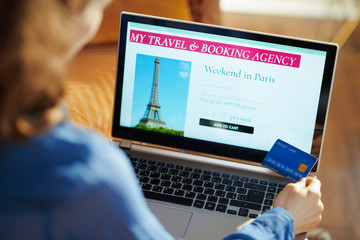woman with online travel site on laptop holding blue credit card