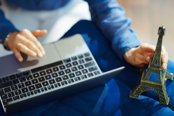 Closeup on woman holding souvenir of eiffel tower with laptop