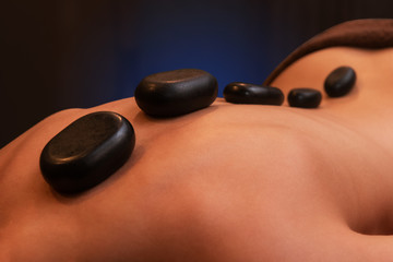 Woman receiving a therapy with hot stones in spa center, closeup photo