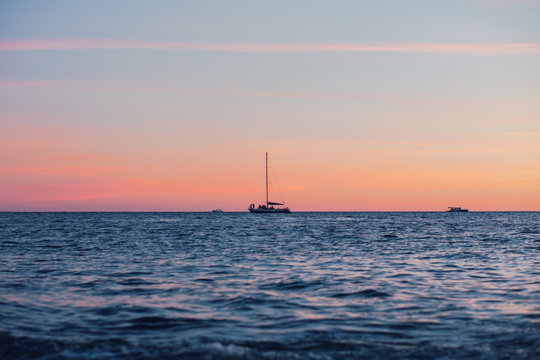 Lonely boat floats on a quiet warm calm sea against the backdrop of a golden sunset on a warm summer evening. Advertising space