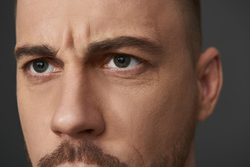 Close up portrait of serious bearded young man posing for camera