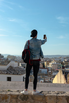 Young man takes a picture with the city in the background