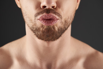 Obraz premium Close up portrait of bearded young man situating against gray background
