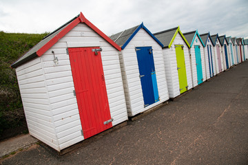 Fototapeta na wymiar Colorful beach huts with moody sky on Goodrington sands beach, Devon, England UK