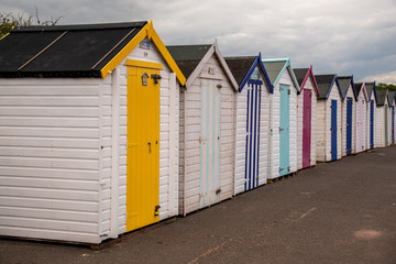 Fototapeta na wymiar Colorful beach huts with moody sky on Goodrington sands beach, Devon, England UK