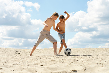 Two brothers playing football against the sky