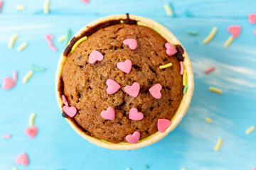 Delicious homemade colorful cupcakes with heart-shaped confectionery close up on a light blue wooden background