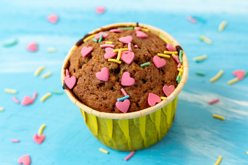 Delicious homemade colorful cupcakes with heart-shaped confectionery close up on a light blue wooden background