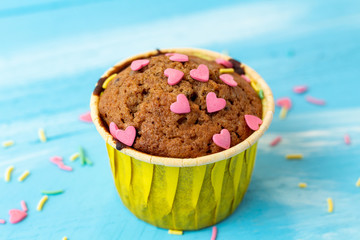 Delicious homemade colorful cupcakes with heart-shaped confectionery close up on a light blue wooden background
