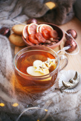 Cup of tea, book, warm pillow, garland light on wooden window sill, Moody seasonal still life. Warm tones, vertical, copy space