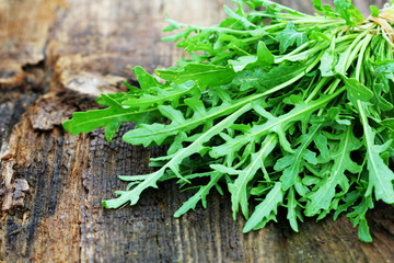 Fresh green arugula leaves on wooden rustic background . Rocket salad or rucola, healthy food, diet. Nutrition concept