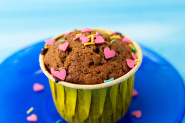 Delicious homemade colorful cupcakes with heart-shaped confectionery close up on a light blue wooden background