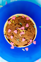 Delicious homemade colorful cupcakes with heart-shaped confectionery close up on a light blue wooden background