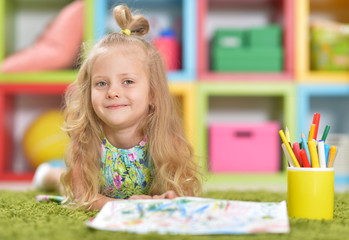 Portrait of cute little girl drawing at home on floor