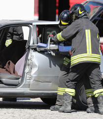 firefighters big shears open a car on the road