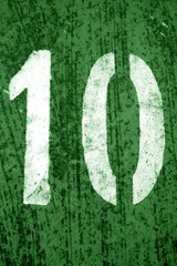 Number 10 in stencil on metal wall in green tone.