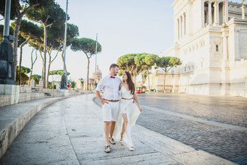 young beautiful couple in white clothes walks in Rome in Italy at sunset