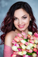 Obraz na płótnie Canvas Beautiful young smiling girl with bouquet of spring flowers of tulips. The best gift is flowers for a birthday and women's day.