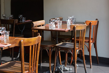 Brown wooden restaurant tables and chairs in sunny summer day
