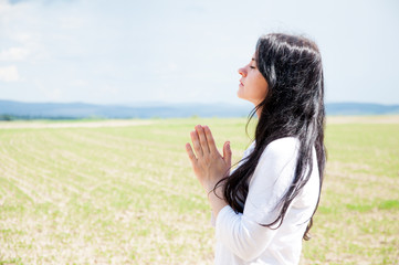 Obraz premium Praying hands with faith belief in God. A woman praying. Closed her eyes. Against the background of sky and clouds.