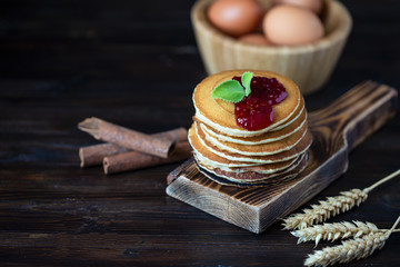 delicious pancakes with jam and mint on a dark wooden table