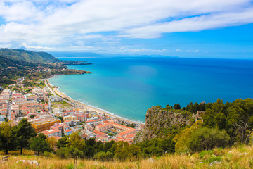 Stunning view over the bay on Tyrrhenian coast by city Cefalu, Sicily, Italy. On the adjacent rocks overlooking blue sea there are medieaval castle ruins Rocca di Cefalu. Popular tourist attraction