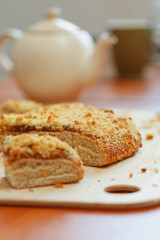 Sweet sand tart with apricot jam. Cut into pieces, lying on a board with a kettle in the background
