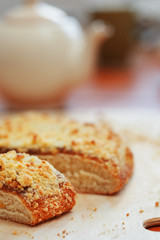 Sweet sand tart with apricot jam. Cut into pieces, lying on a board with a kettle in the background