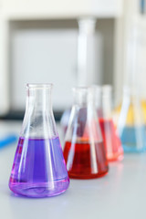 Chemical laboratory flask with blue purple-pink liquid stand on the table