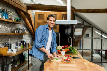 Happy handsome man cooking in kitchen at home