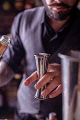 barman preparing cocktai and pours liquid into the jigger in a cocktail bar