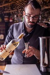 barman preparing cocktai and pours liquid into the jigger in a cocktail bar