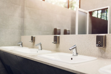 Fototapeta na wymiar Modern interior design in public toilet. New sinks, taps with mirror and window above