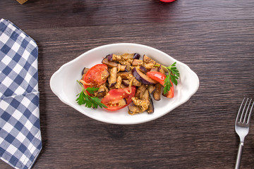 Vegetable salad with fried eggplants and tomatoes on wooden table
