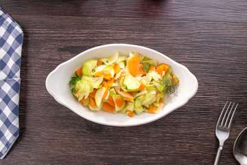 Vegetarian ragout of summer vegetables zucchini, carrots in a white bowl on a wooden table