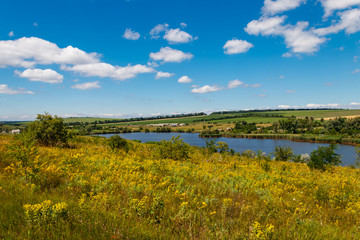 Fototapeta premium Summer landscape with beautiful lake, green meadows, hills, trees and blue sky