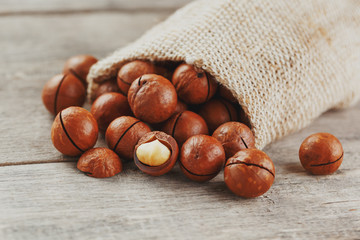 Macadamia nut on a wooden table in a bag, closeup, top view