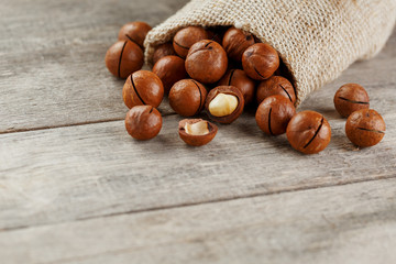 Macadamia nut on a wooden table in a bag, closeup, top view