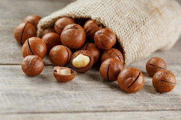 Macadamia nut on a wooden table in a bag, closeup, top view