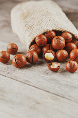 Macadamia nut on a wooden table in a bag, closeup, top view