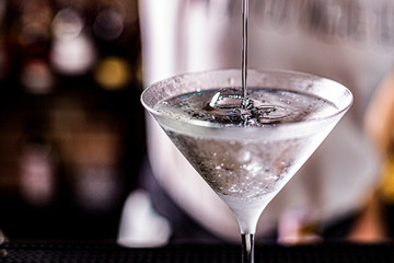 vodka martini isolated on a black background with an olive splashing and air bubbles - obrazy, fototapety, plakaty
