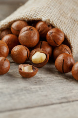 Obraz premium Macadamia nut on a wooden table in a bag, closeup, top view